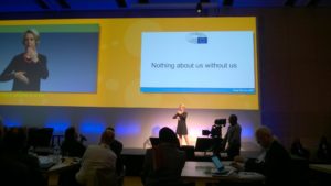 Helga Stevens på Fundamental Rights Forum 2016. Använder teckenspråk. På skärmen texten Noting about us without us.