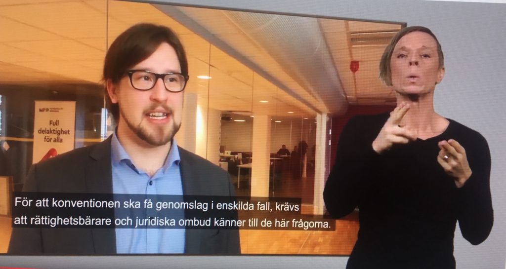 Ola Linder och teckenspråkstolk på filmduk